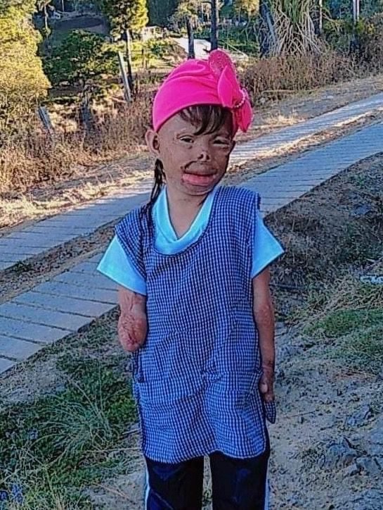 A young girl standing on a country road in her home country