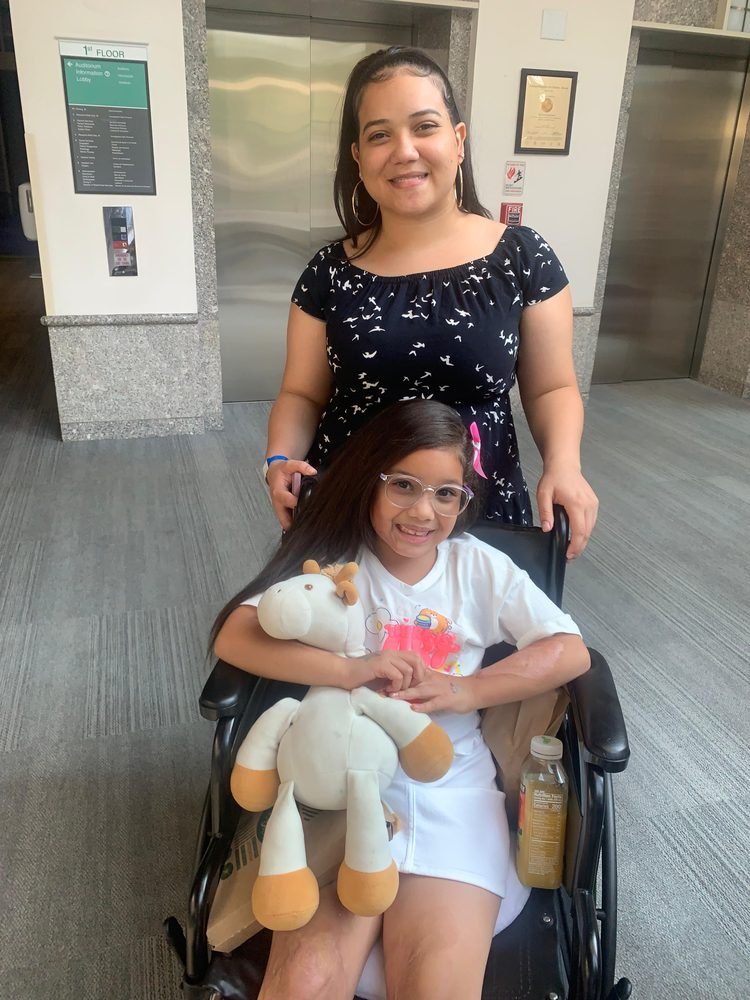 A girl in a wheelchair with a caring volunteer